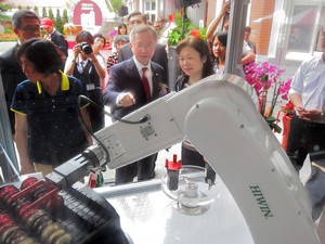 三信商銀董事長廖松岳(圖中)、金管會銀行局副局長呂蕙容(右一) 討論機器人如何煮咖啡。