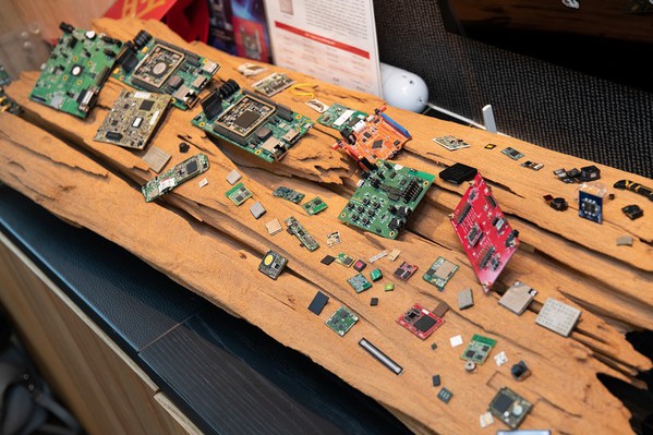 圖二 : 這塊木板上是梁文隆三十年來的成果與經歷，包含各種微型化的無線模組，以及全世界第一顆的電子麥克風封裝。