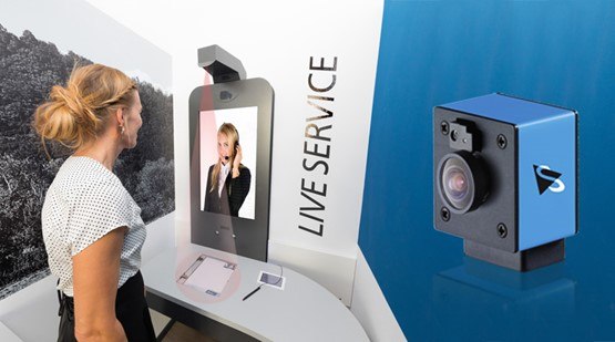 图一 : 顾客在德国一家银行使用互动式柜员机：头顶上方安装的工业自动对焦相机，即使在文件不完全平放状况下仍能提供最隹图像。