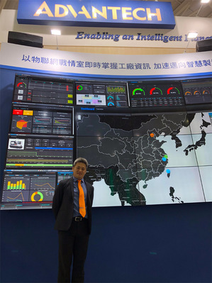 研華市場開發經理吳偉立站在16面電視牆打造的戰情室前，十分壯觀（攝影/王景新）